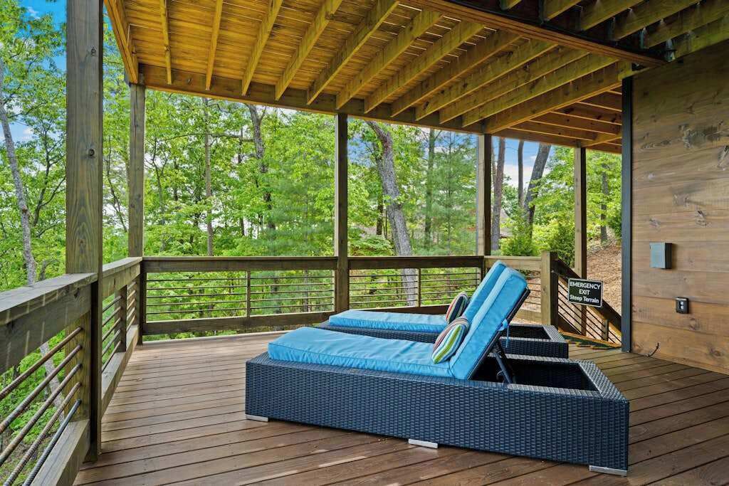A covered outdoor seating area with a view of a forest.