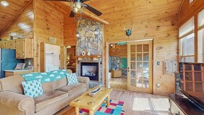 A wooden cabin interior with a sofa, coffee table, fireplace, and a television. - Time Out Blue Ridge - Hot tub (Blue Ridge)