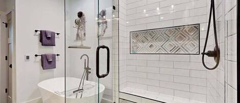 A modern bathroom with a glass-enclosed shower, a freestanding bathtub, and a tiled shower area.