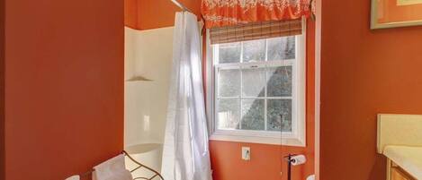 Ein Badezimmer mit Fenster, Duschvorhang, Handtuchhalter und Toilette.