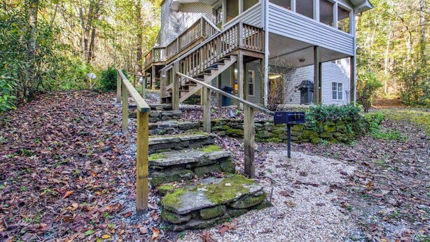 Une cabane en bois à deux étages, avec un escalier en pierre menant à une véranda.