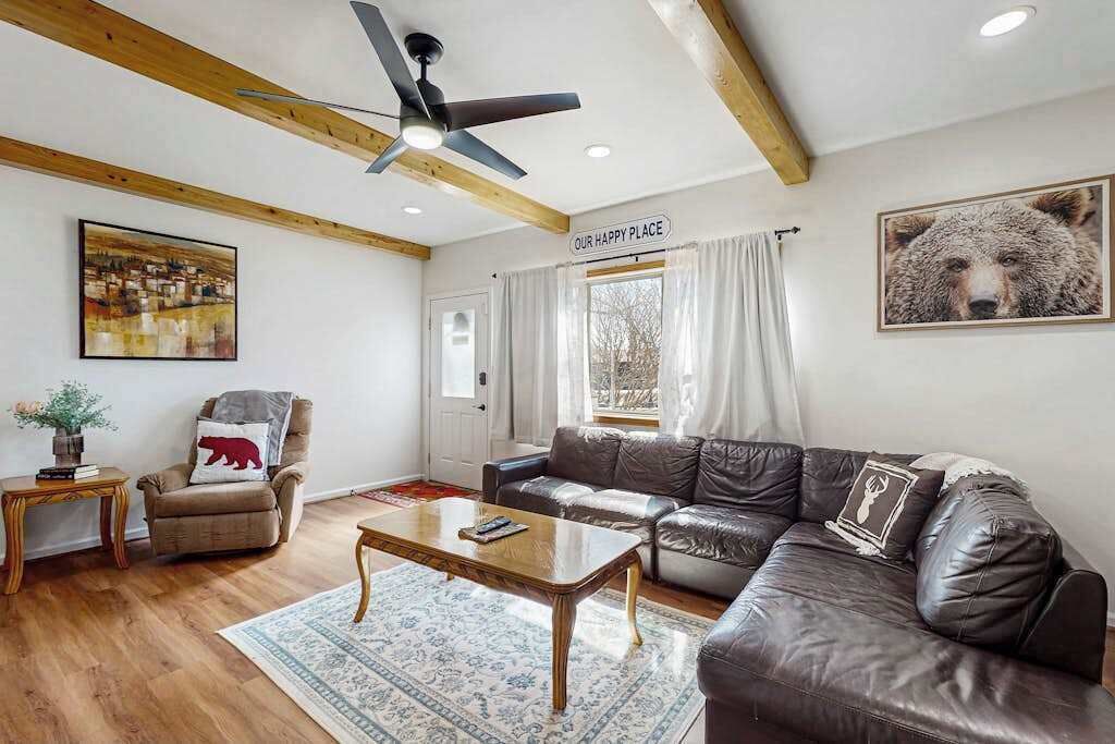 A living room with a sofa, armchair, coffee table, and a ceiling fan.