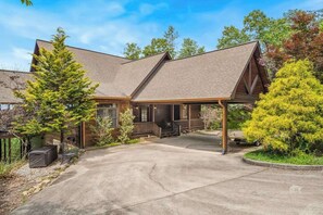 A two-story lodge with a covered porch, a driveway, and surrounding trees. - Endless Views Retreat (Mineral Bluff)