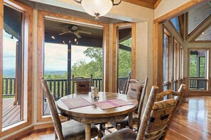 A wooden deck with a round table and chairs, large windows, and a ceiling fan. - Endless Views Retreat (Mineral Bluff)