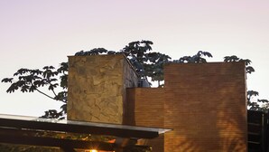 A building with a stone facade, a wooden pergola with lights, and potted plants.