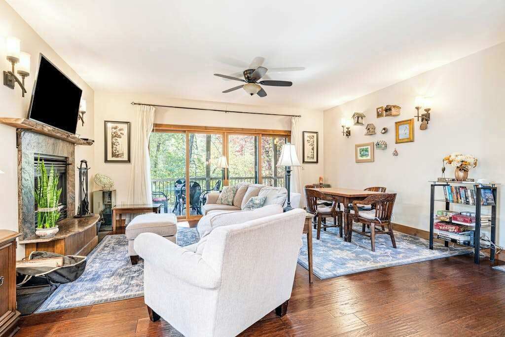 A living room with a fireplace, a sofa, a dining table, and a ceiling fan.