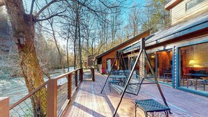 A wooden deck with outdoor seating, overlooking a river and surrounded by trees. - Life's a River Stays (Ellijay)