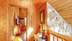 A wooden interior with a stone wall, a staircase, and a table with a bowl and candle. - Life's a River Stays (Ellijay)