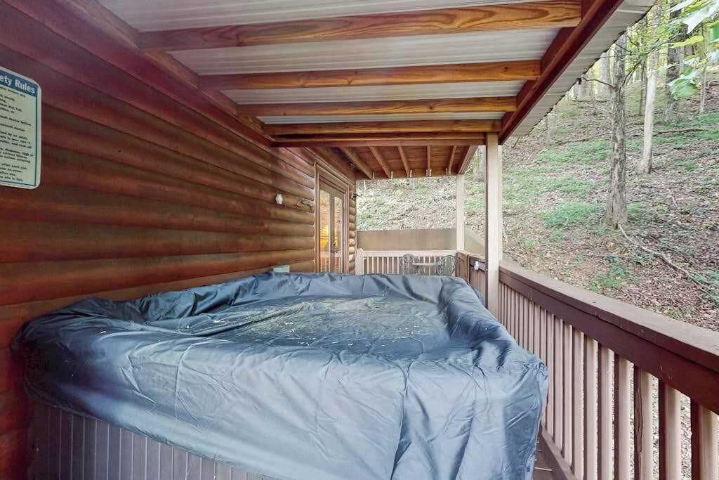 A hot tub under a wooden deck with a view of a forested area.