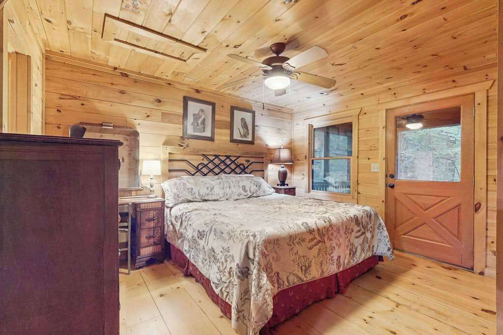 Ein Schlafzimmer einer Holzhütte mit Bett, Kommode und Tür.