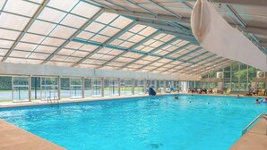 Una piscina interna con soffitto in vetro, zona solarium trasparente e diverse unità di condizionamento.