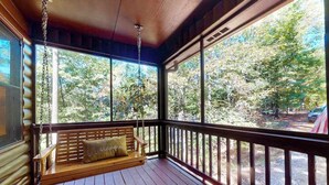 Un portico in legno con un'amaca e vista sugli alberi.