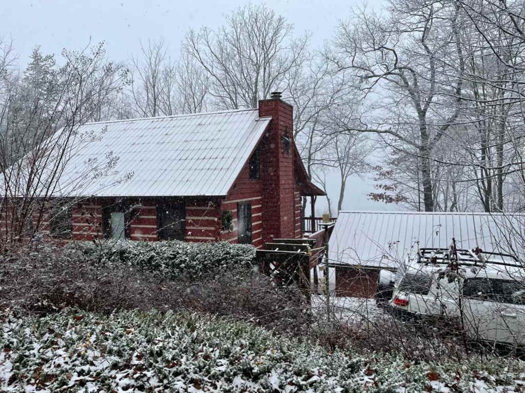 A brick building with a metal roof, surrounded by snow-covered ground and trees.