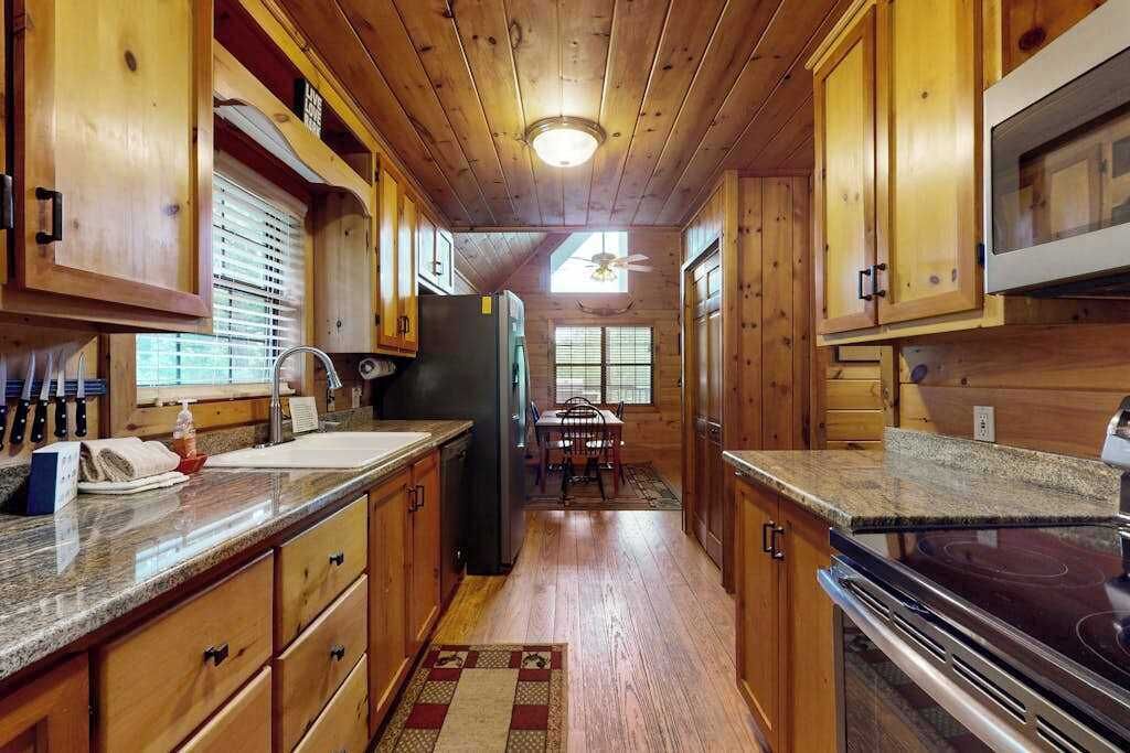 A kitchen with wooden cabinets, granite countertops, a refrigerator, and a stove.