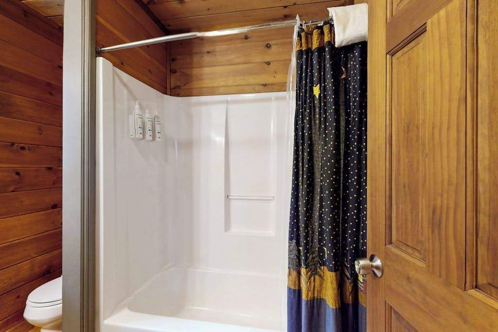 Ein Badezimmer mit Holzpaneelen, einer weißen Badewanne, einem Duschvorhang und einer Tür.