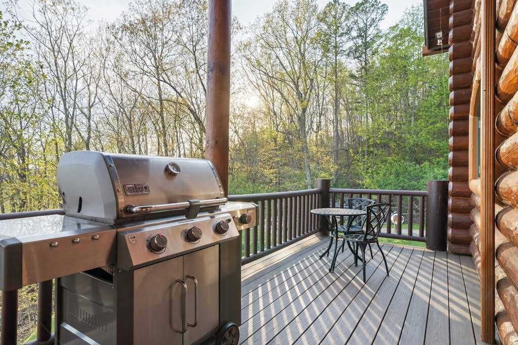 A wooden deck with a grill, a table, and chairs.