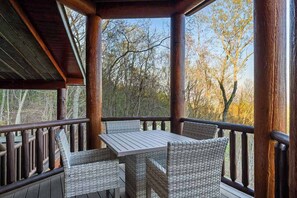 A covered outdoor seating area with a table and chairs, surrounded by wooden railings. - Majestic Lodge Retreat (Morganton)