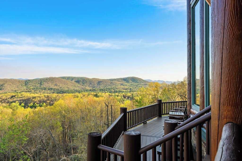 Une terrasse en bois avec une balustrade donnant sur une vallée boisée.