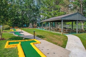 Un parque con mesas de picnic, un área de juegos y un pabellón cubierto.