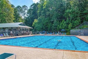 Una piscina con sillas de descanso y un edificio al fondo.