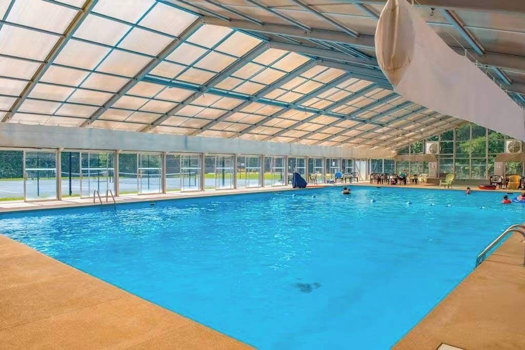 Una piscina interior con techo de cristal, zona de bordes despejada y múltiples carriles.