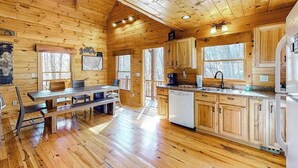 Ein Holzblockhaus-Interieur mit Essbereich, Küche und großen Fenstern.