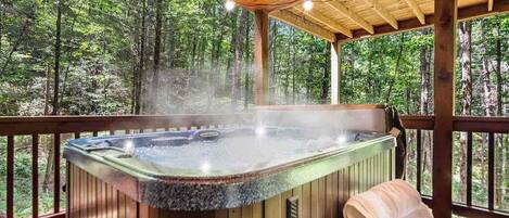 A hot tub on a wooden deck with a forest view.