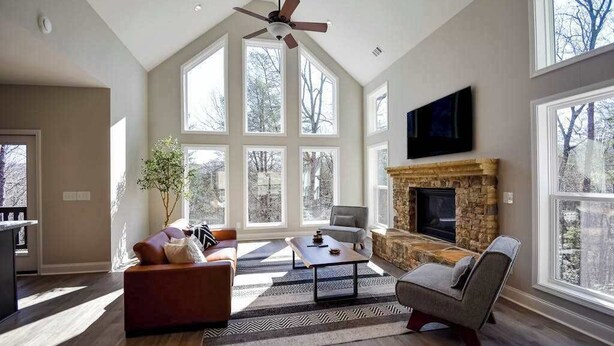 Un salón amplio con chimenea, ventanas grandes y un ventilador de techo.
