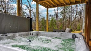 Un jacuzzi con terraza de madera y vista a los árboles.