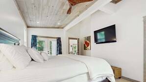 A bedroom with a large bed, a TV mounted on the wall, and a wooden ceiling. - The Hidden Haven Stay (Blue Ridge)