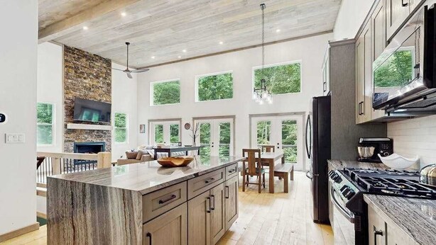 A modern kitchen with a large island, built-in appliances, and large windows offering views of greenery. - The Hidden Haven Stay (Blue Ridge)