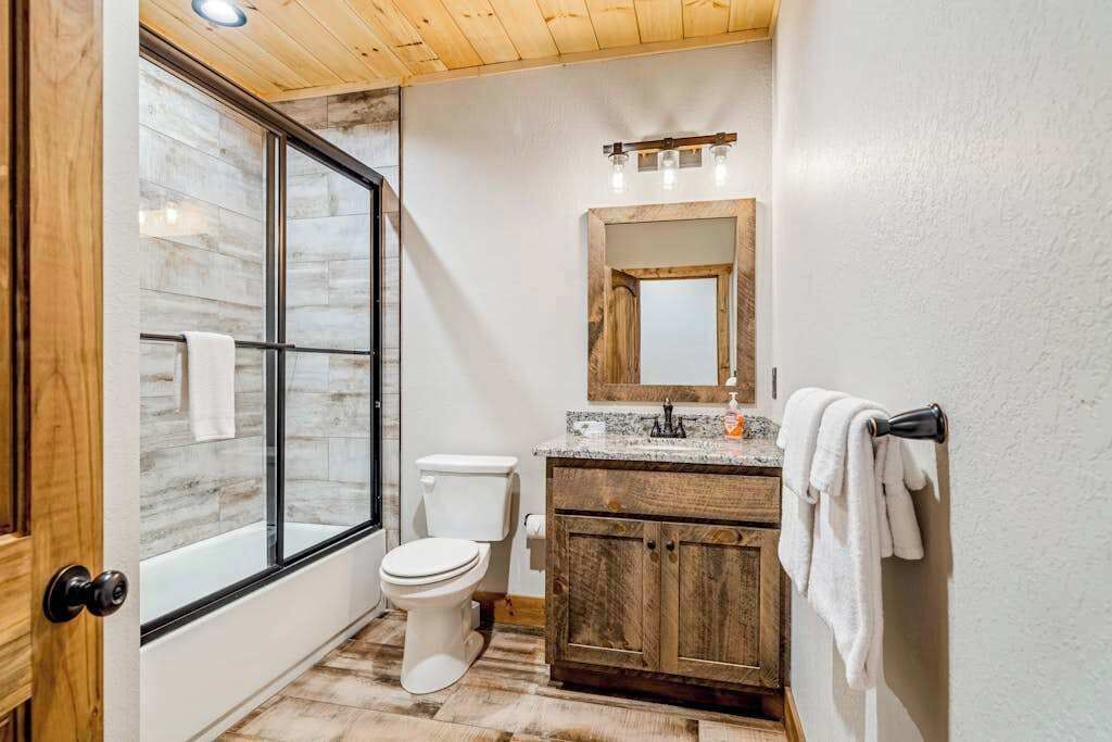 A bathroom with a glass shower enclosure, a toilet, a vanity with a mirror, and a towel rack.