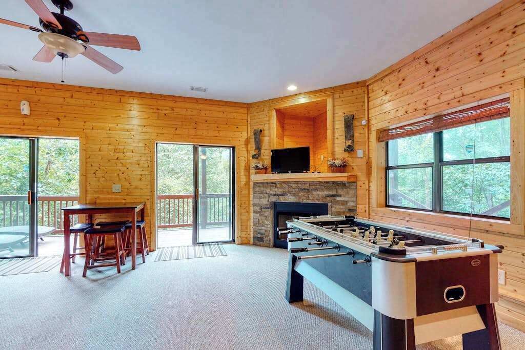A wooden interior with a foosball table, a television, and a fireplace.