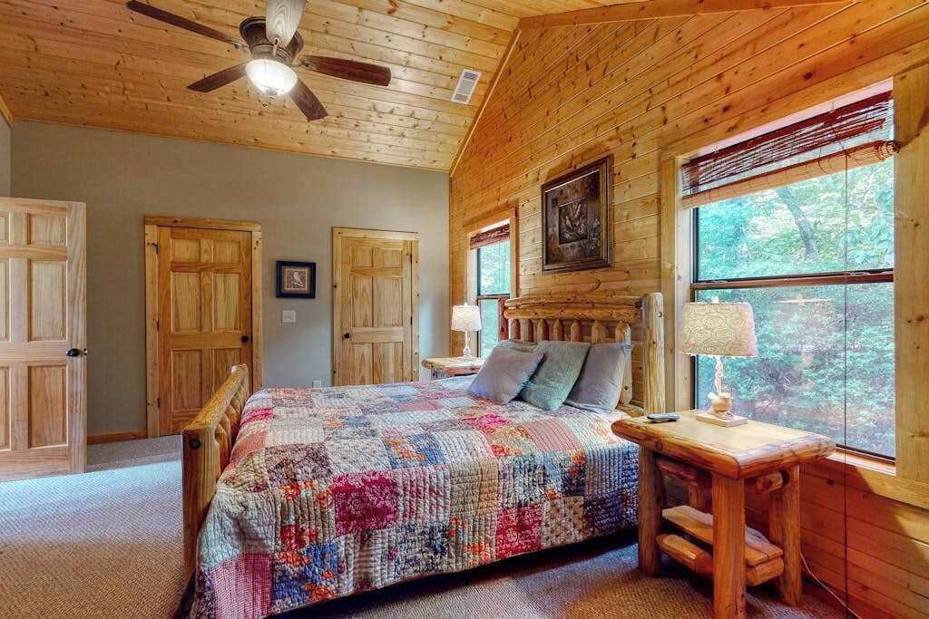 Un dormitorio de cabaña de madera con una cama, un escritorio y una ventana.