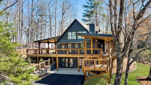 A two-story log cabin with a deck, surrounded by trees. - The Lodge with 5 individual en-suites (Blairsville)