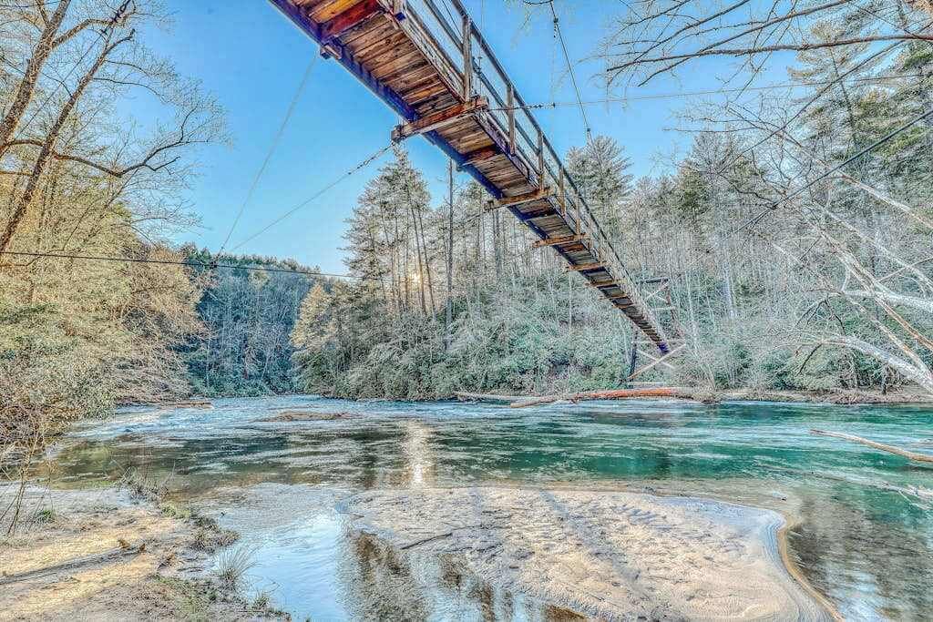 A river with a wooden bridge, surrounded by trees and clear water.