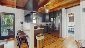 Eine moderne Küche mit Holzboden, Edelstahlgeräten und Blick ins Freie.