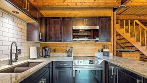 Une cuisine moderne dotée d’appareils électroménagers en acier inoxydable, de meubles de cuisine en bois foncé et d’un plafond en bois.