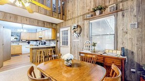 Een houten interieur met een eettafel, stoelen, een keukenhoek en een vide.