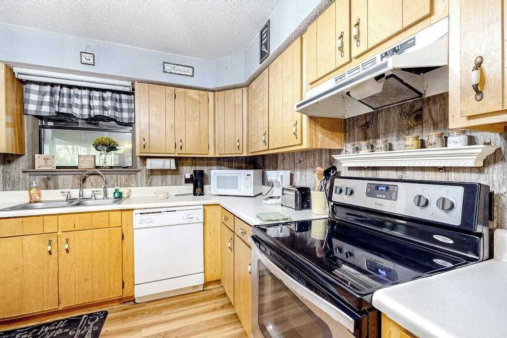 A compact kitchen with wooden cabinets, a white dishwasher, a black stove, and a microwave.
