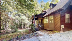 Een houten chalet met een veranda, een vlag en een kleine tuin.