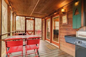 A wooden deck with a table and chairs, a grill, and framed certificates on the wall. - Bear in the Woods Stay (Blue Ridge)
