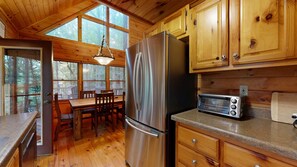 Una cucina in legno con un frigorifero in acciaio inossidabile, un tostapane e un tavolo da pranzo con sedie.