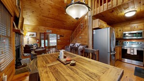 Ein Holzblockhaus-Interieur mit Esstisch, Küchenbereich und Kamin.