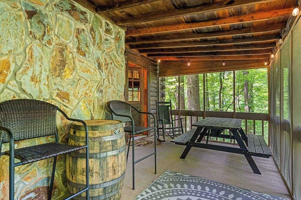 Eine rustikale Holzhütte mit Steinwänden, Holzbalkendecke, einem Picknicktisch und Stühlen.