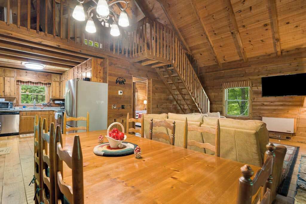 Un interior de madera con una mesa de comedor, sillas, un sofá, una escalera y una zona de cocina.