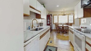 A kitchen with white cabinets, a dining area with a table and chairs, and a chandelier. - Cool River Condo I Stay (Helen)