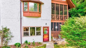 A two-story building with a white exterior, a red door, and a small porch area. - Cool River Condo I Stay (Helen)