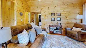 Un interior de madera con un sofá de cuero marrón, un tapete estampado y una estantería de madera.