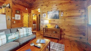 A wooden cabin interior with a sofa, coffee table, and a fireplace. - Ogana Ridge Getaways (Ellijay)